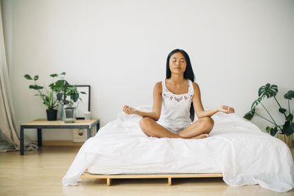 Mediation benefits: Young woman practicing yoga on bed