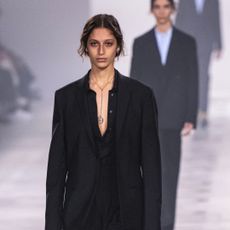 a model walks the Fendi runway wearing a pendant necklace beneath a black shirt