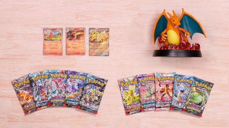 Charizard statue, cards, and Pokemon card booster packs laid out on a wooden surface