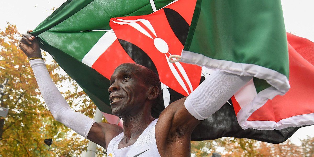 Eliud Kipchoge carrying his flag across the finish line