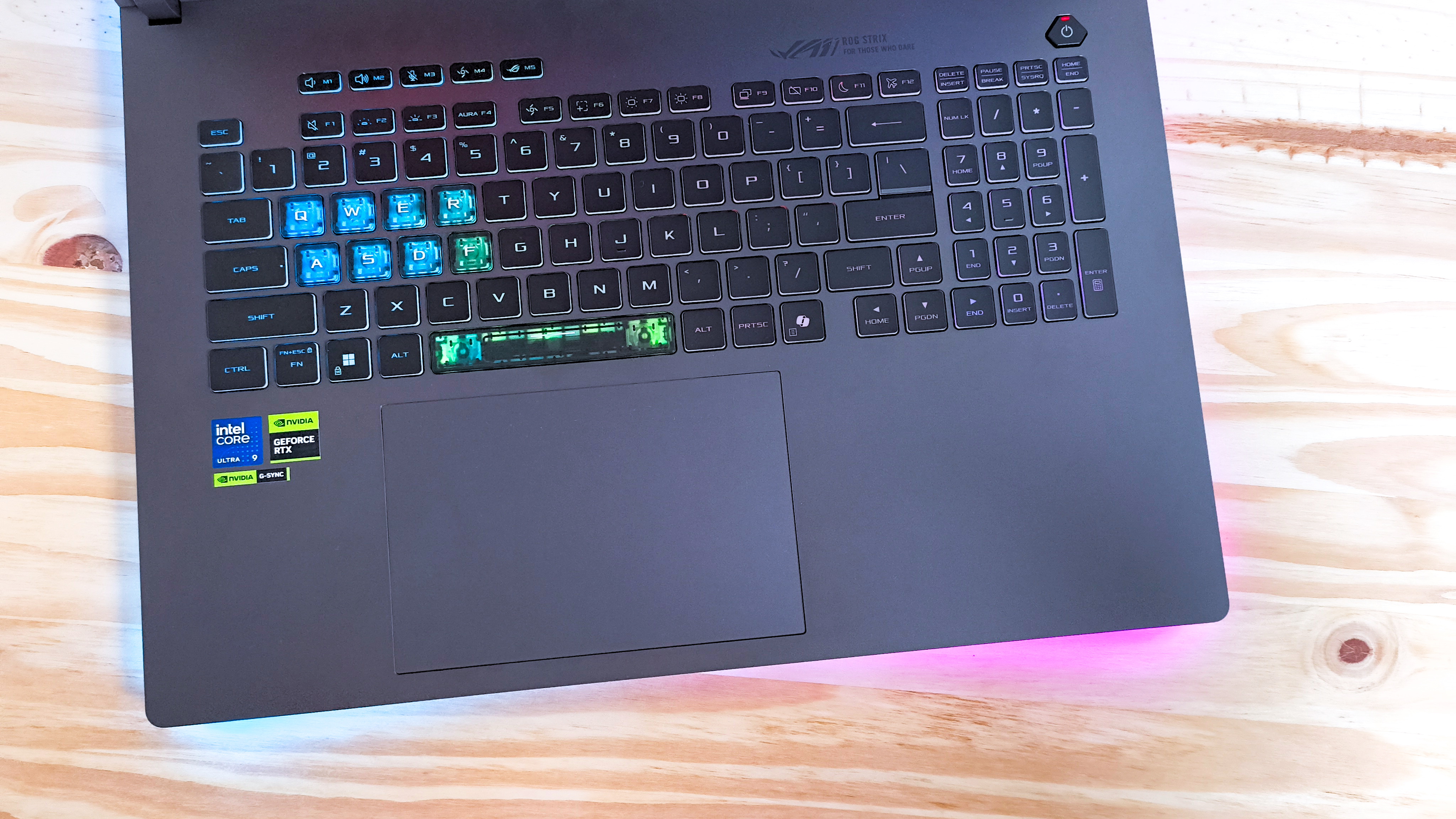 The keyboard deck of the Asus ROG Strix G18 seen from above on a wood table
