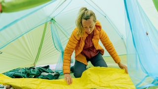 Woman inflating sleeping pad in a tent