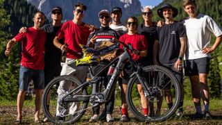 Group of people holding an e-MTB in front with mountains behind