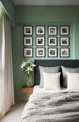 A green toned bedroom with small black and white photographs