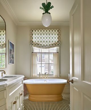 neutral batroom with striped floor tiles and a yellow bath tub