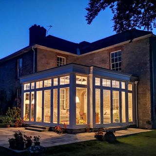 An exterior shot of a conservatory lit up from inside