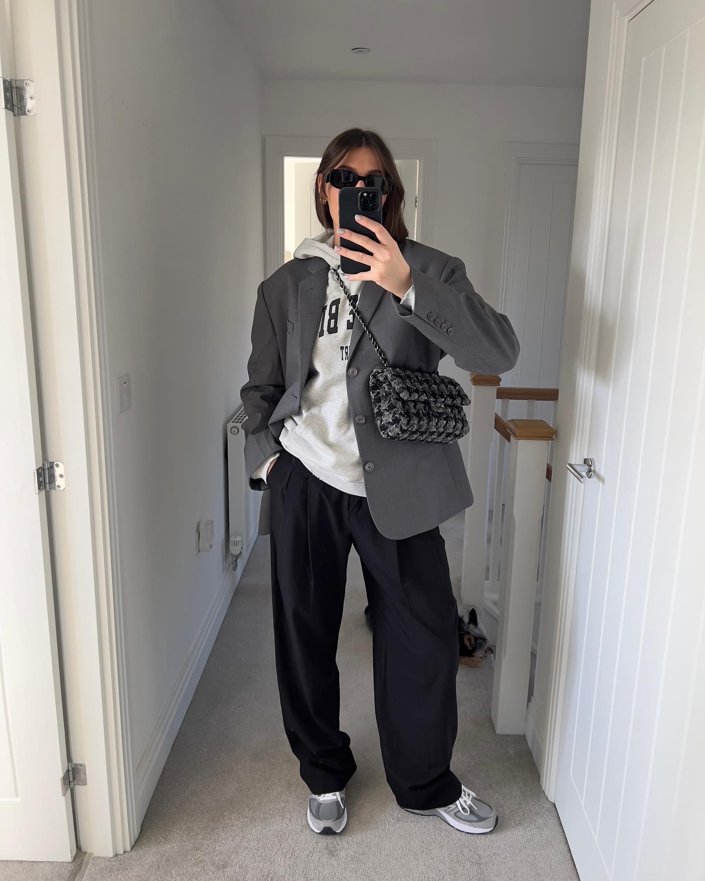 Influencer wears a grey blazer with black trousers and trainers