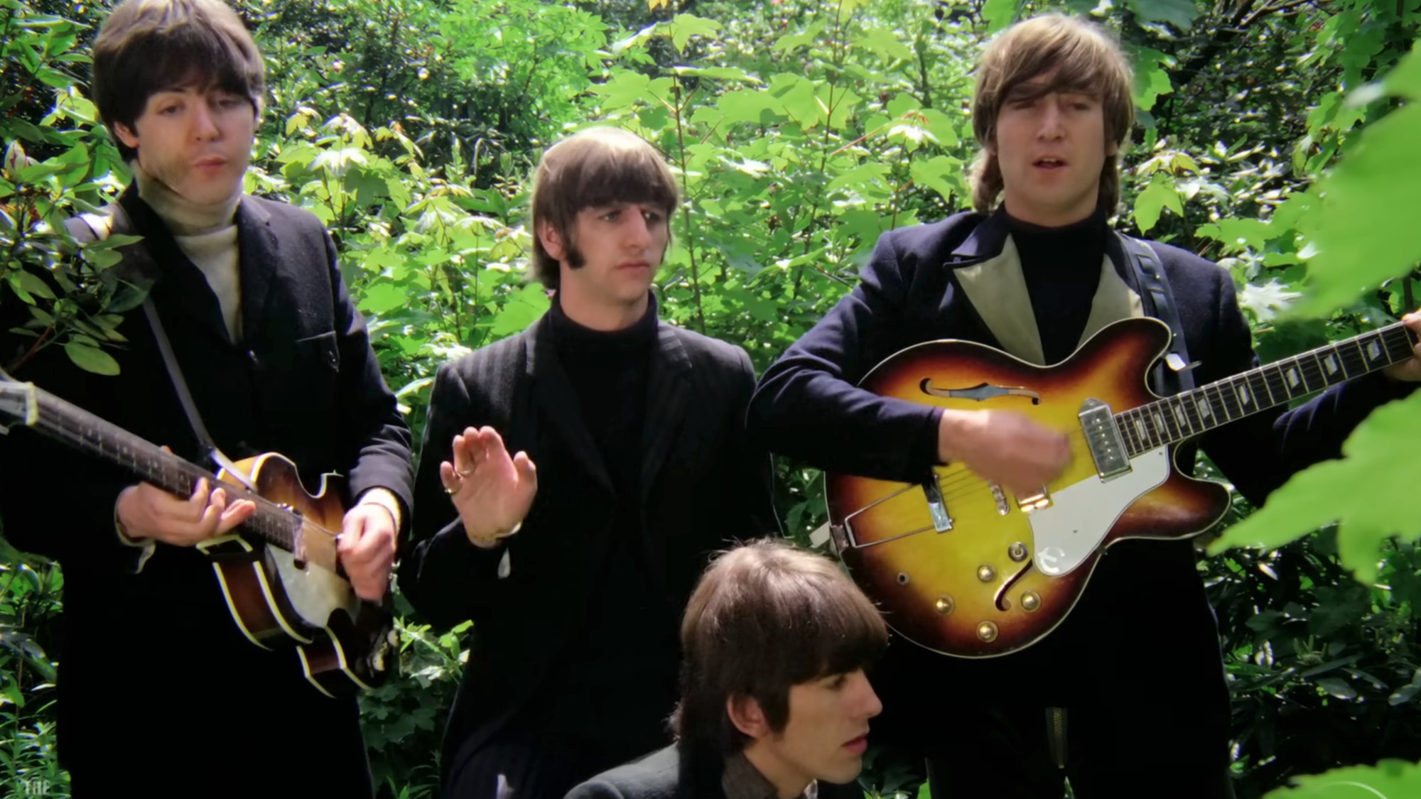 The four Beatles in dark suits playing their instruments.