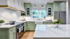 A mint green kitchen with veined quartz countertops 