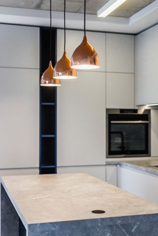 A kitchen with metallic light above the island