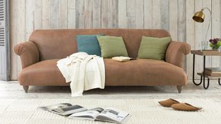 Light brown aged leather sofa in neutral living room with grey shiplack walls