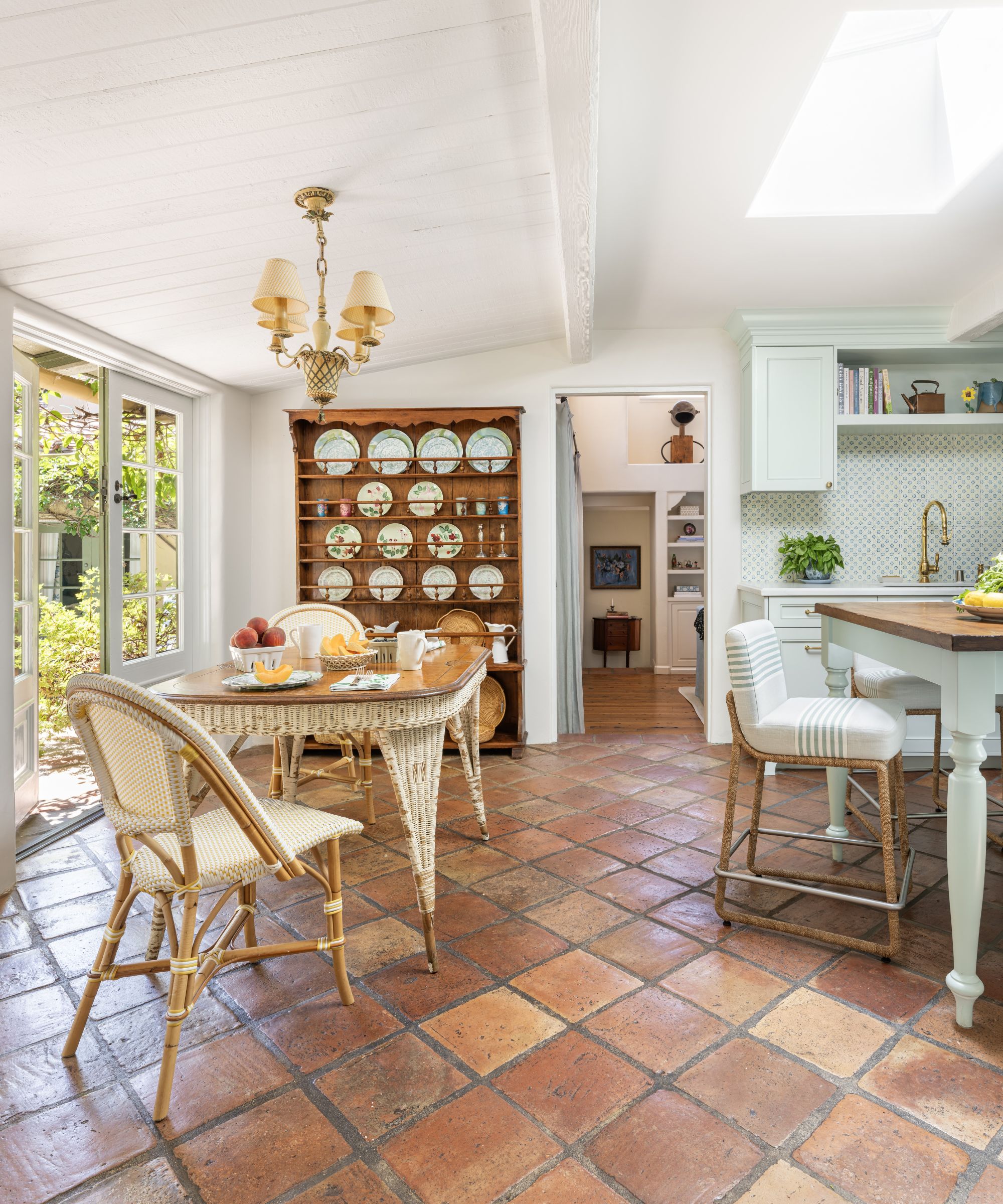 A transitional kitchen with terracotta floor tiles, and antique plate rack, and a vintage dining table