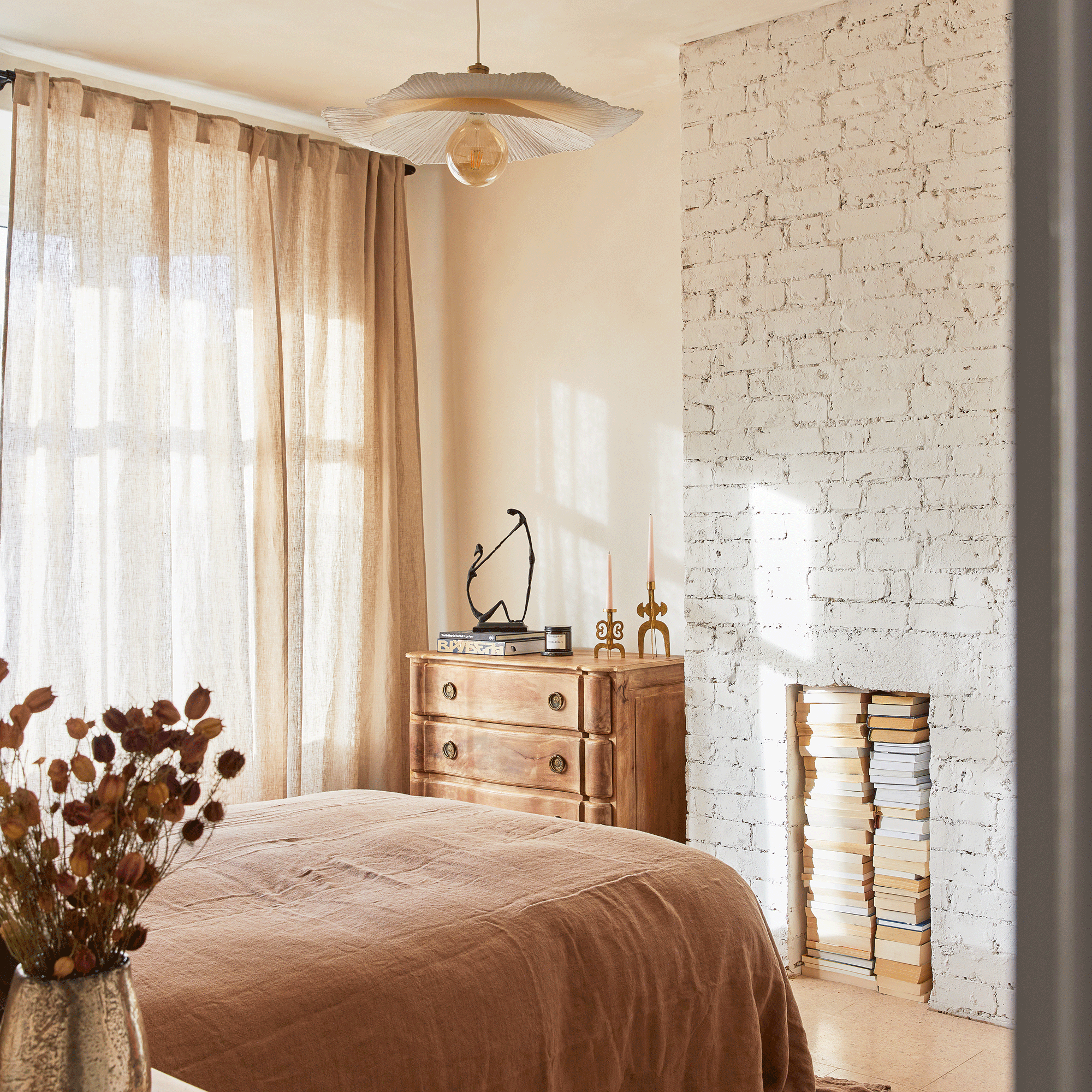 a neutral bedroom with a white painted exposed brick chimney breast