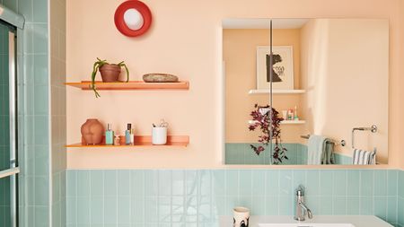 Coral bathroom space with blue tile and orange shelving