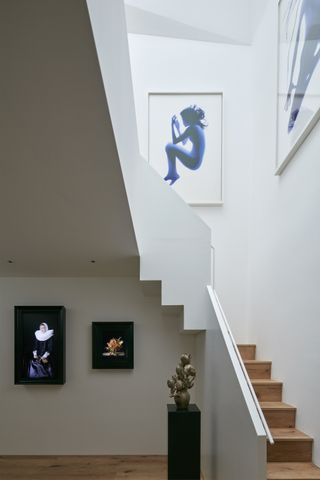 Art displayed on white walls by the stairs