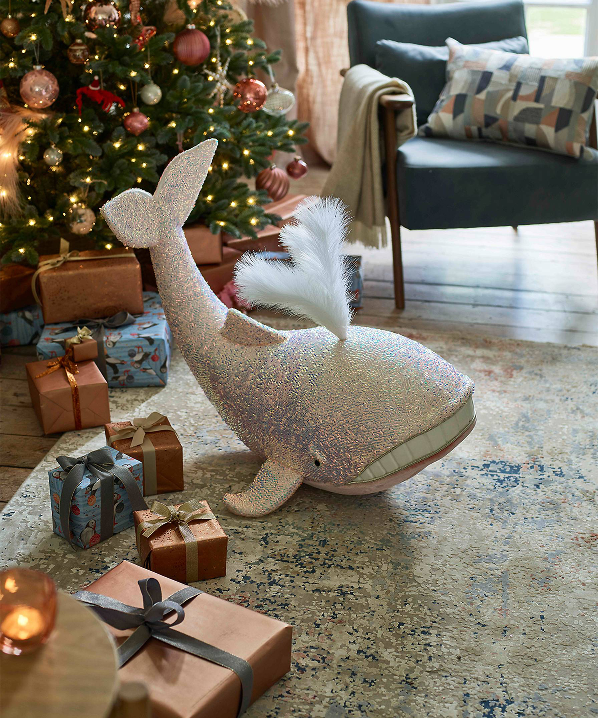 A contemporary Christmas-themed living room with patterned rug, plush whale toy and decorated Christmas tree