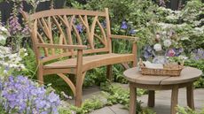 A wooden bench on a patio with glorious summer planting
