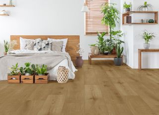 bedroom with wood look vinyl floor, double bed and houseplants