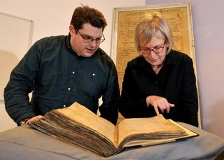 Gary Brannan, archivist, and Sarah Rees Jones examine one of the registers of the Archbishops of York.