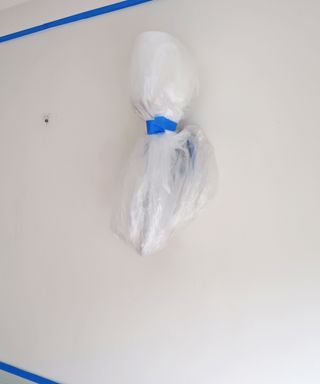 Dust sheet secured with masking tape to protect a wall light during painting