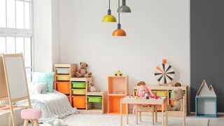 child's room showing play area with wooden storage, desk and three ceiling pendants coloured yellow, orange and grey