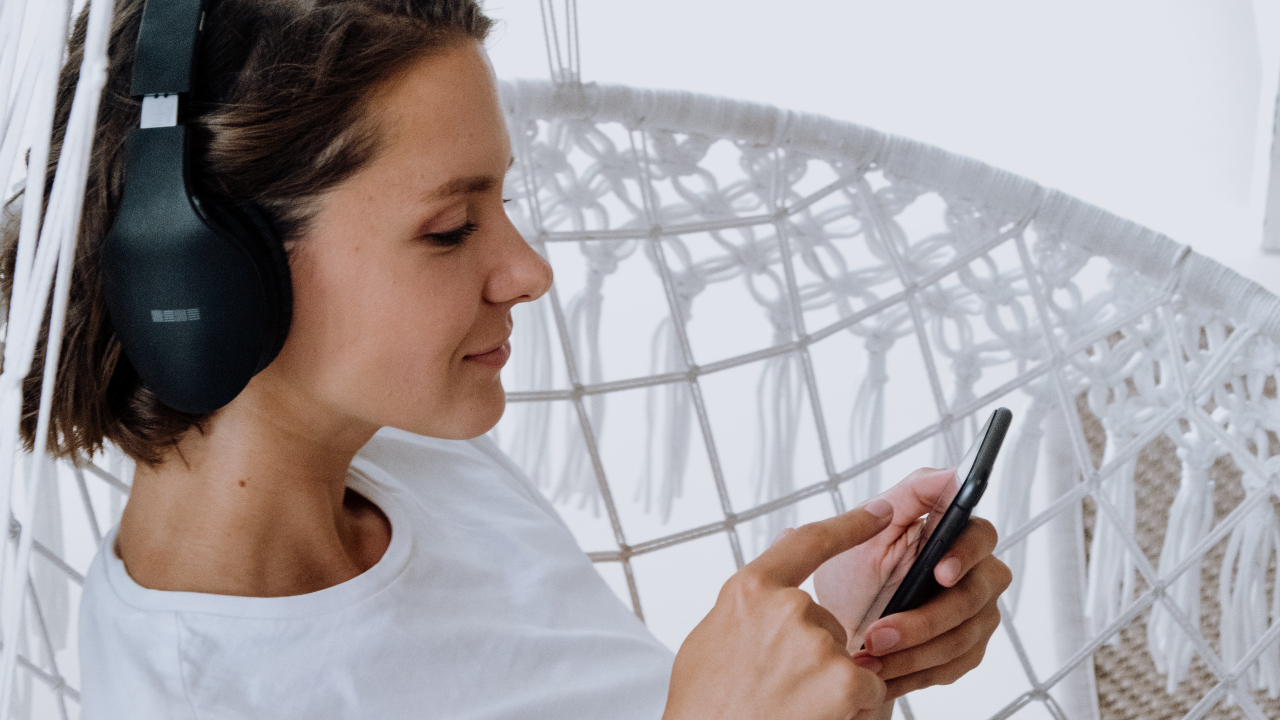 woman holding an iPhone on a white hammock