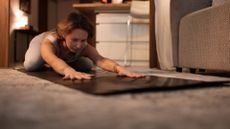 Woman practising yoga for sleep on a mat in living room at night