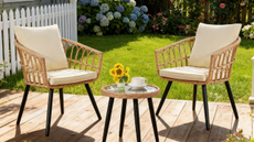 two chairs and a small table on a porch in a backyard