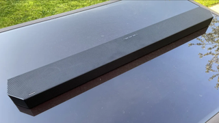 En Samsung HW-Q800C soundbar ligger utomhus på ett svart bord.