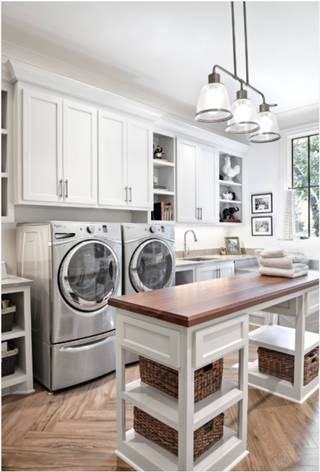 Large utility room with freestanding island with wooden countertops. The island also has storage space for baskets and other nooks.