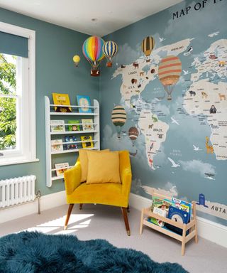 blue playroom with yellow chair, blue rug, map on wall, hot air balloons, book shelf on wall