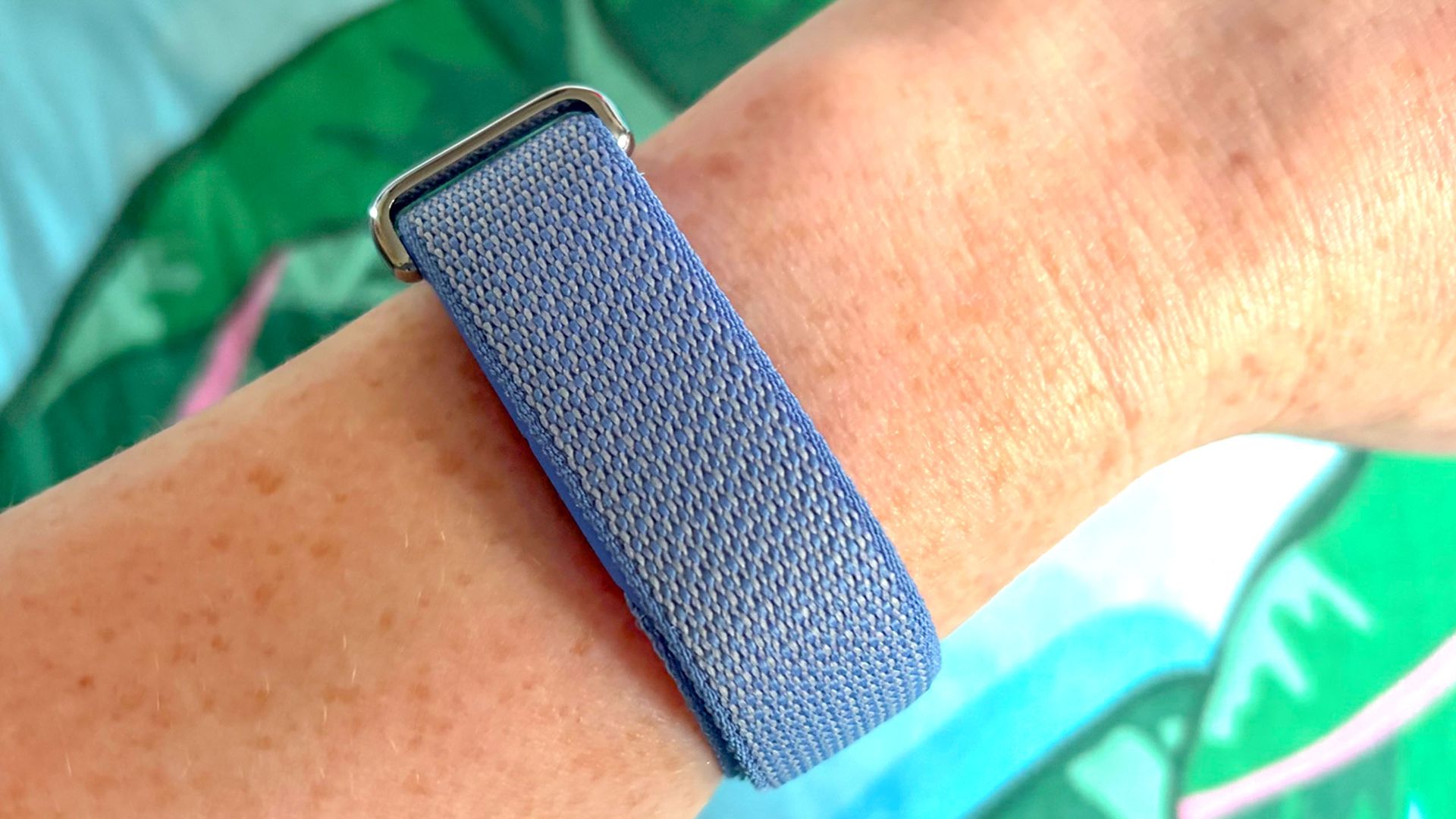 A close up of a hand wearing the Fitbit Air