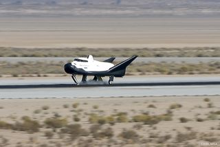 dream chaser shuttle landing on a runway, surrounded by desert