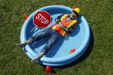 A construction working lying down in a paddling pool
