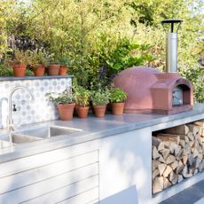 outdoor kitchen with grey counter wash basin plant pots and wood