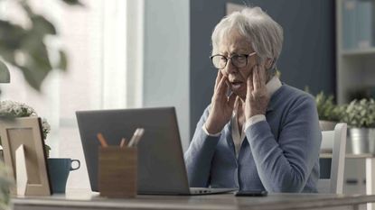 Photo of an older woman looking distressed at her laptop computer