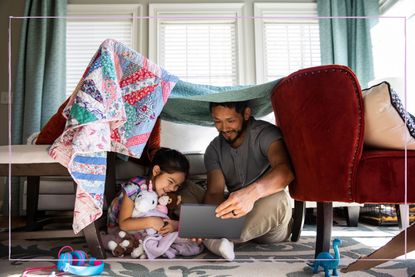 dad reading with daughter under den with toys