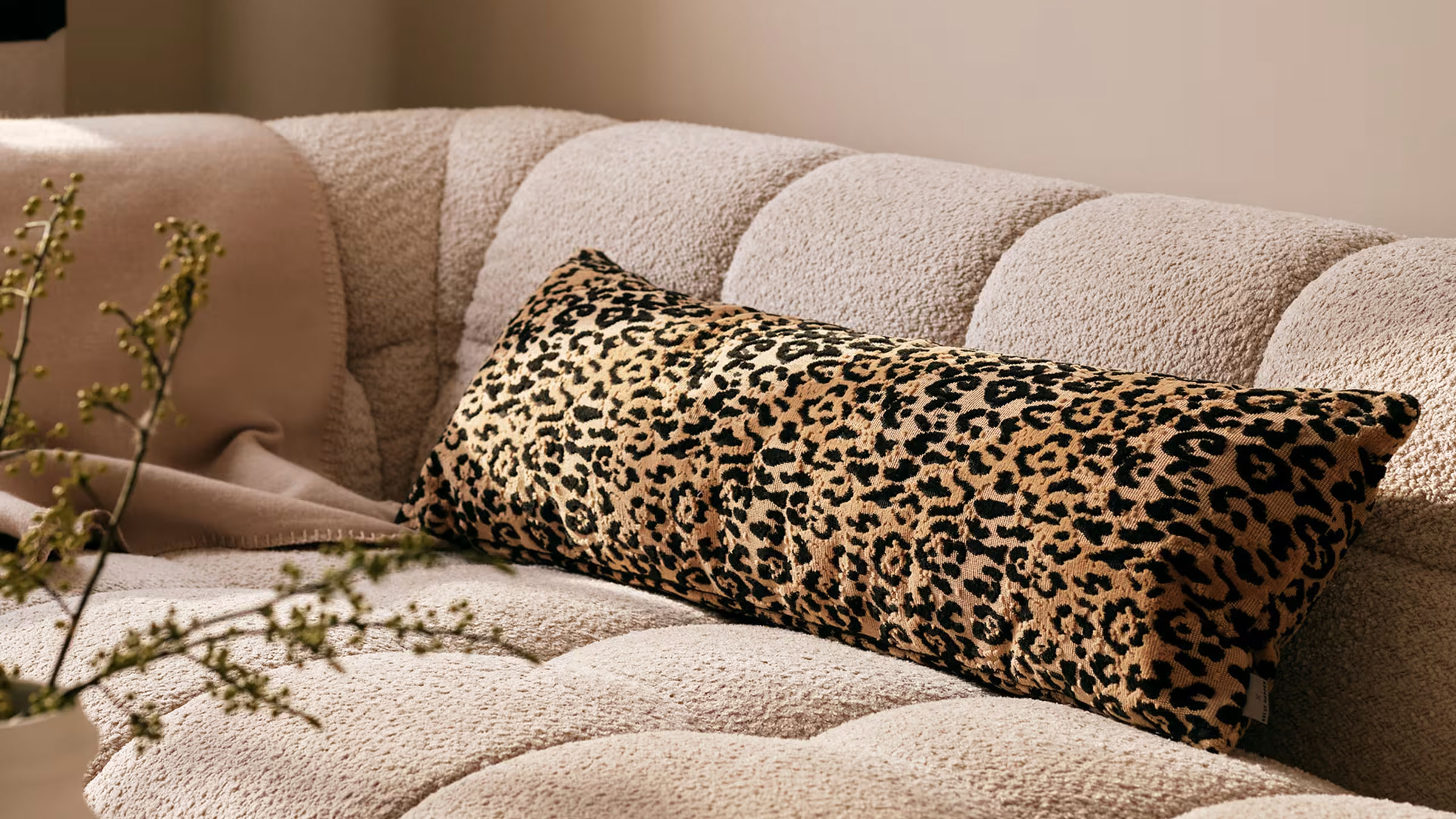 Leopard print bolster cushion on a boucle sofa