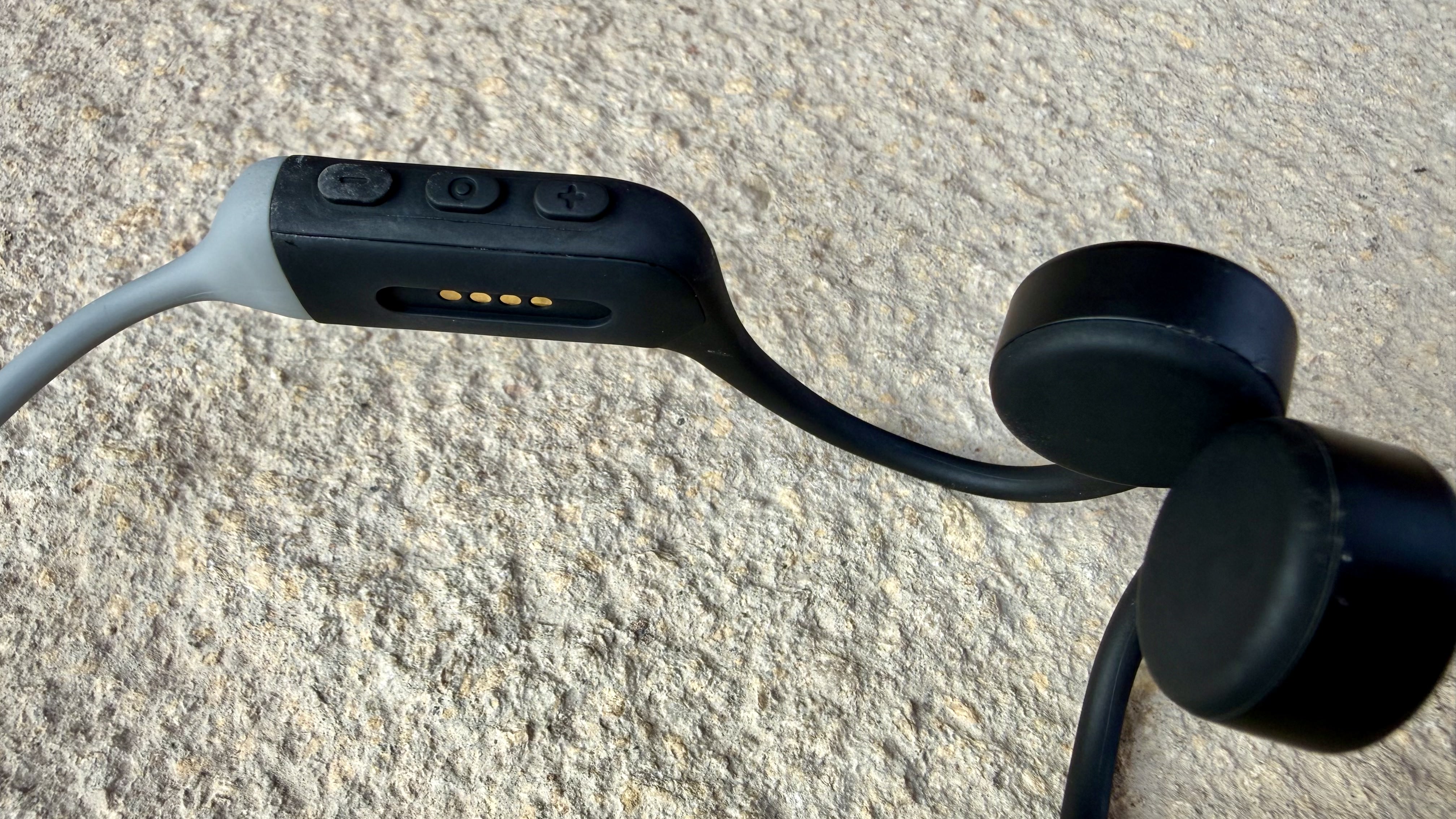 The h2o audio tri run bone conduction headphones on a stone surface