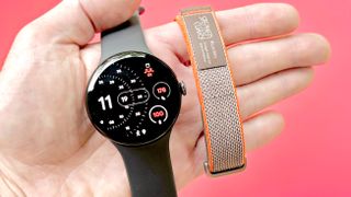 Close-up of the Google Pixel Watch 4 and Fitbit Air in a user's hand against a bright red background