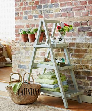 a-frame ladder as towel storage in front of exposed brick wall
