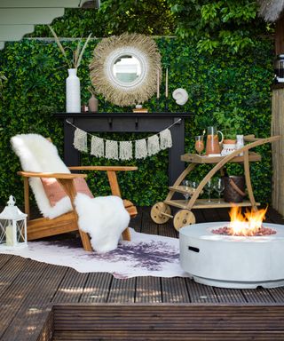 Outdoor patio decking with Adirondack seating and faux-fur throw, white round stone fire-pit, classic wooden drinks cart, rug, macrame