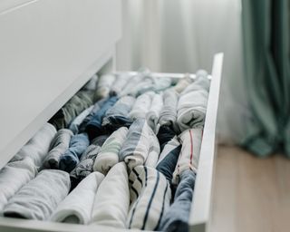 Open bedroom drawer with neatly folded t-shirts