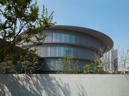 The exterior of the He Art Museum. The circular building, surrounded by trees.