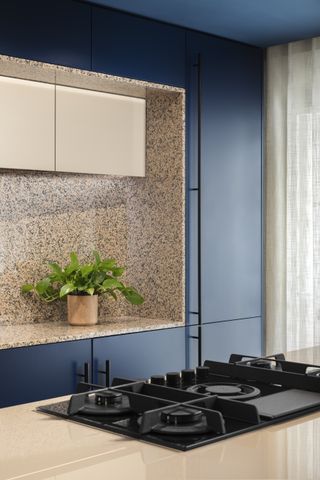 A kitchen with salmon pink countertop and navy blue cabinets