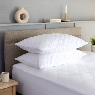 A mattress protector and two pillows on top of a mattress in a contemporary bedroom