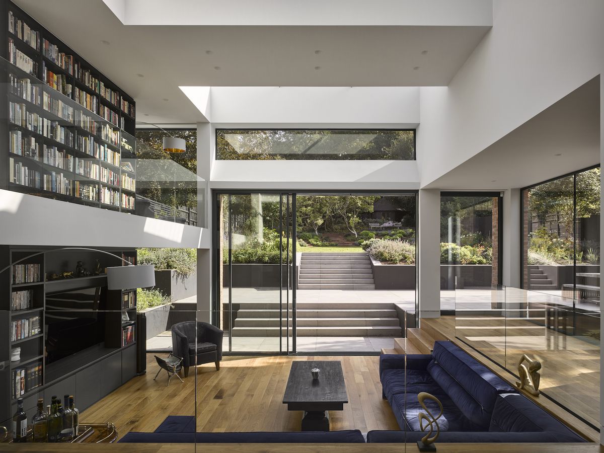 large living room with double-height bookshelf and sliding doors to garden