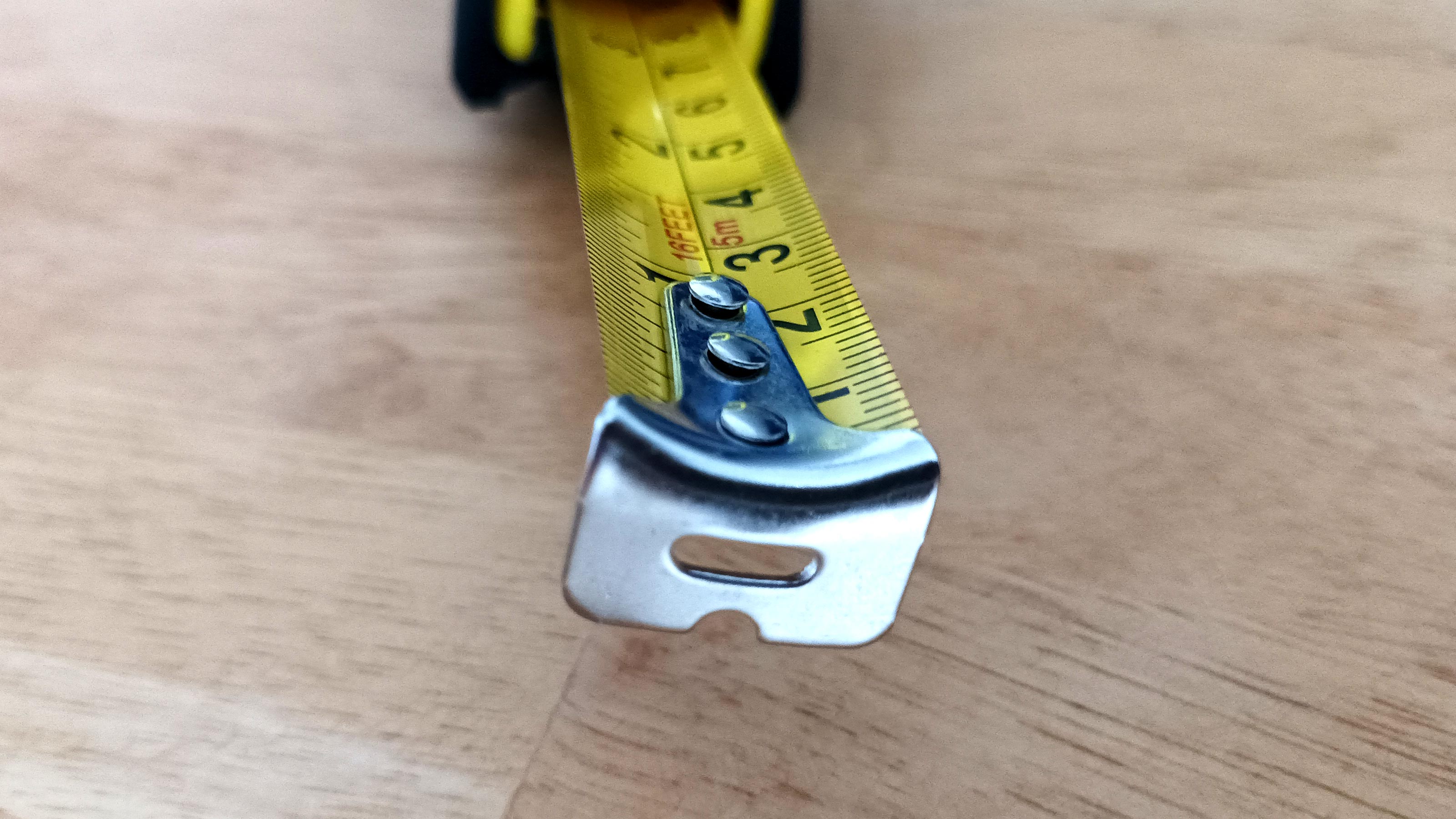 Close up of tape measure hook on wooden background