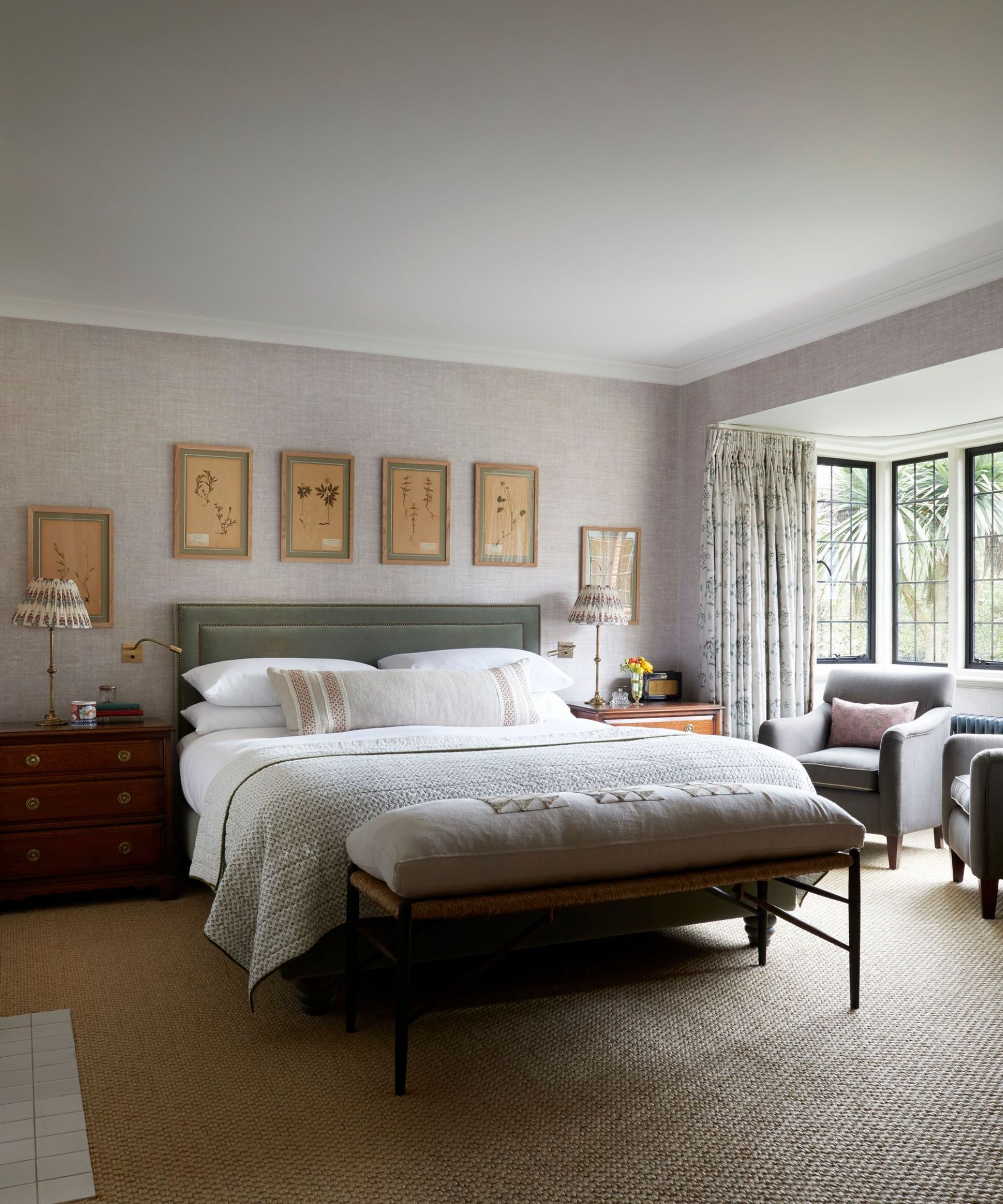 Bedroom with jute carpet, green velvet headboard, foot stool, bedside tables with printed lampshades