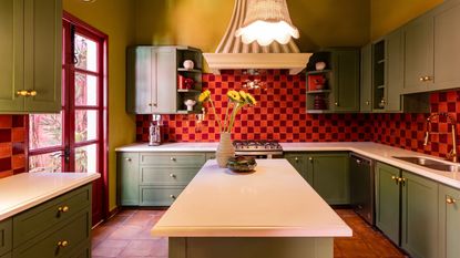 Image of a kitchen that has olive and yellow green paint on the walls and cabinets with a red orange and magenta red tile and trim.